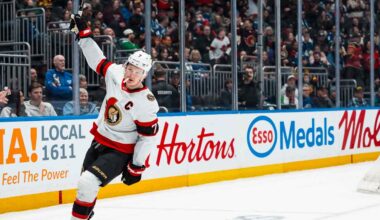 Ottawa Senators captain Brady Tkachuk skating on the ice with his stick raised during a game, amidst escalating NHL trade rumors about his future.