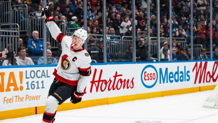 Ottawa Senators captain Brady Tkachuk skating on the ice with his stick raised during a game, amidst escalating NHL trade rumors about his future.