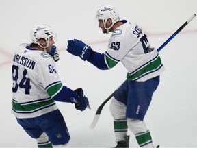 Vancouver Canucks center Linus Karlsson, left, congratulates center Max Sasson after his goal against the Colorado Avalanche in the first period of an NHL hockey game Wednesday, April 1, 2026, in Denver.