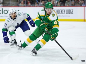 Minnesota Wild defenseman Quinn Hughes, right, skates with the puck as Vancouver Canucks centre Teddy Blueger defends.