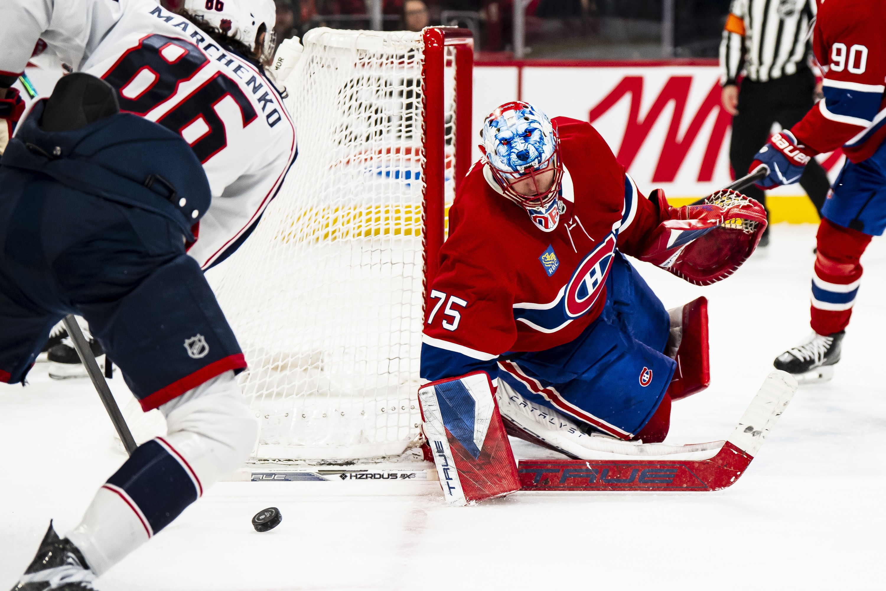 Hockey goaltender blocks a shot with his stick held flat on the ice. 