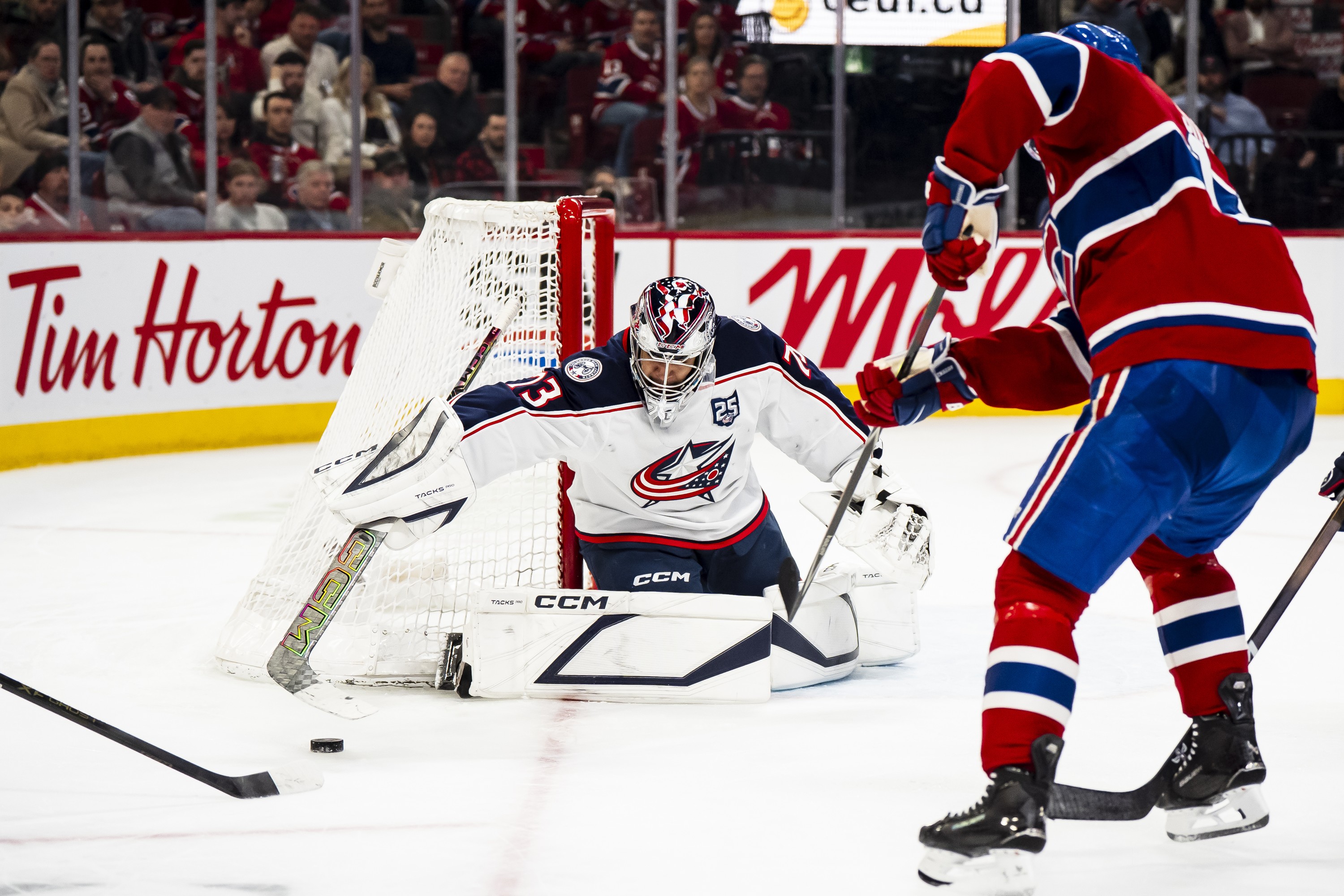 Goaltender sweeps out his stick to make a save against an opponent.