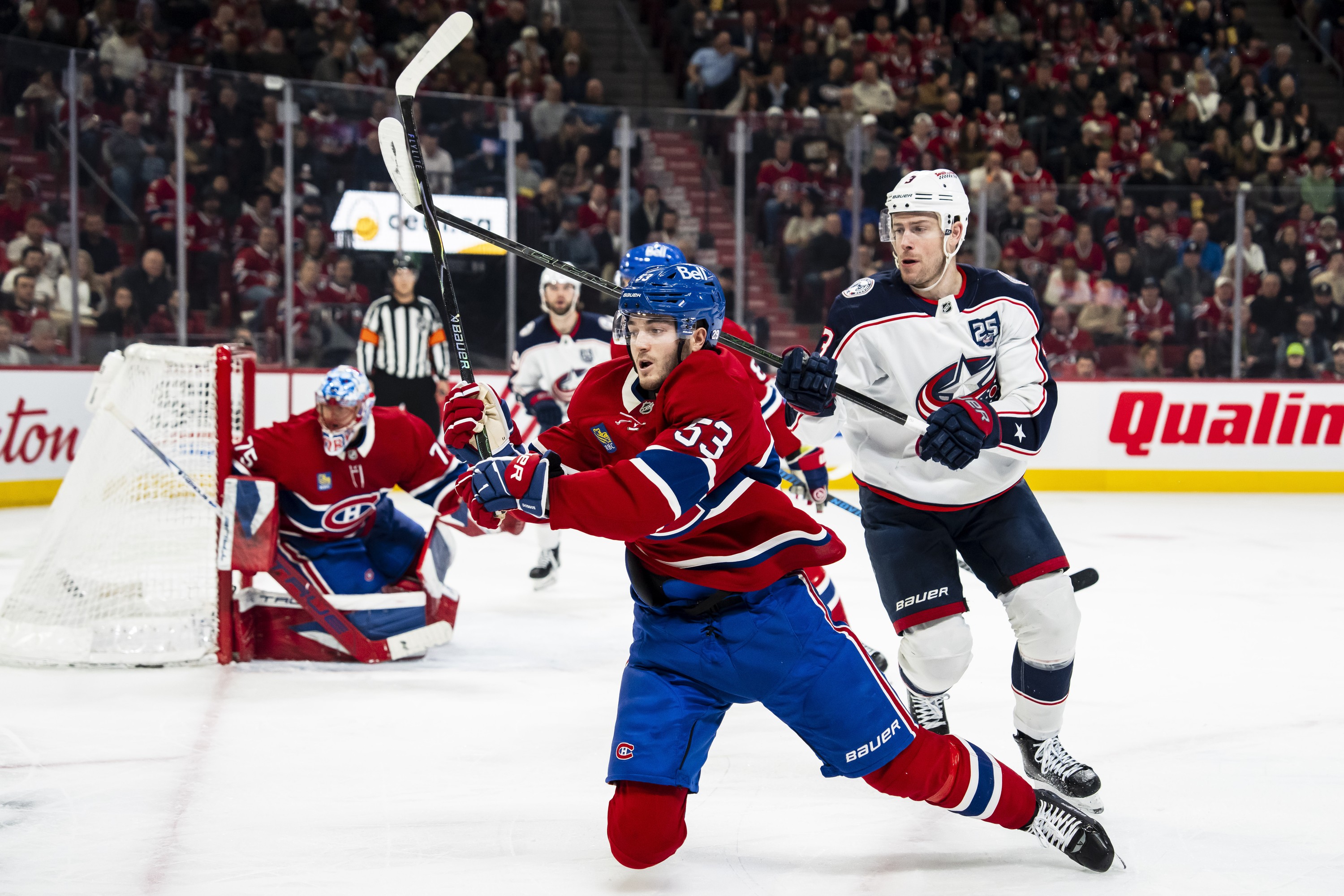 Hockey player falls to the ice while defending against an opponent. 