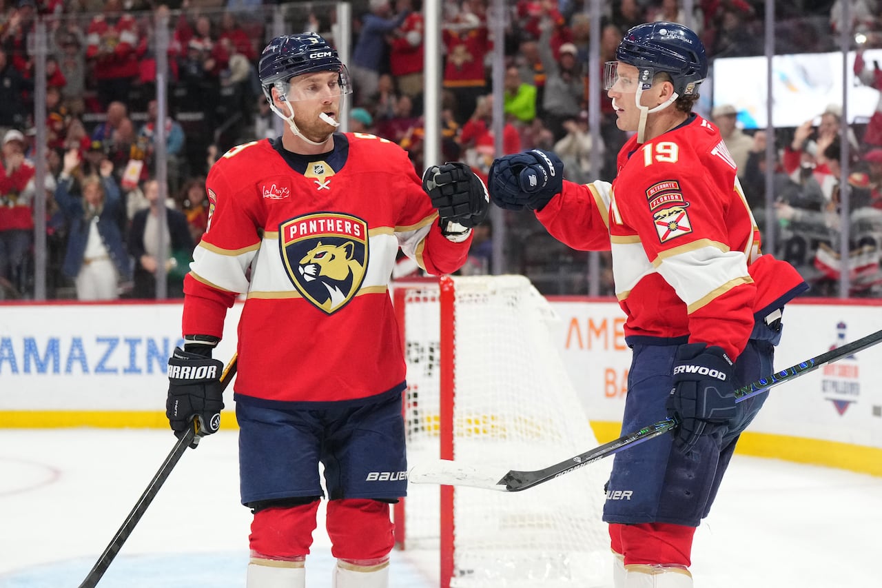 Two hockey players tap gloves to celebrate a goal.