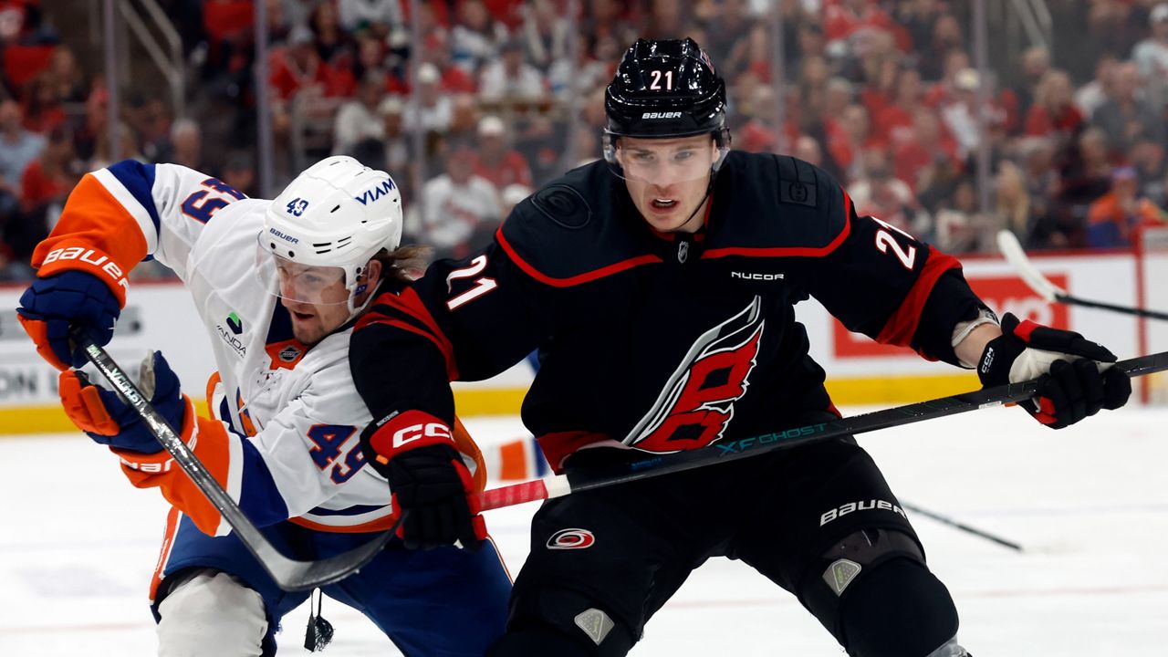 Carolina Hurricanes' Alexander Nikishin (21) battles for position with New York Islanders' Max Shabanov (49) during an NHL hockey game in Raleigh, N.C., Saturday, April 4, 2026. (AP Photo/Karl DeBlaker)
