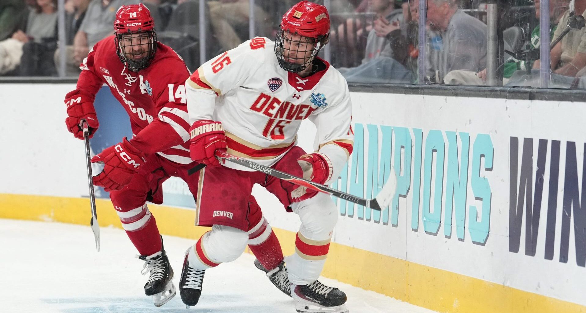 Apr 11, 2026; Las Vegas, Nevada, United States; Wisconsin Badgers defenseman Joe Palodichuk (14) and Denver Pioneers forward Kyle Chyzowski (16) battle for control of the puck during the second period in the championship game of the NCAA men's ice hockey Frozen Four at T-Mobile Arena