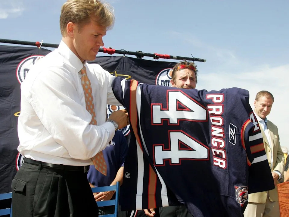  Newly acquired Edmonton Oilers defenceman Chris Pronger tries on his new jersey presented to him by Oilers captain Jason Smith, as Kevin Lowe looks on outside of the Edmonton Oilers head office during a press conference to introduce the the newly signed players.