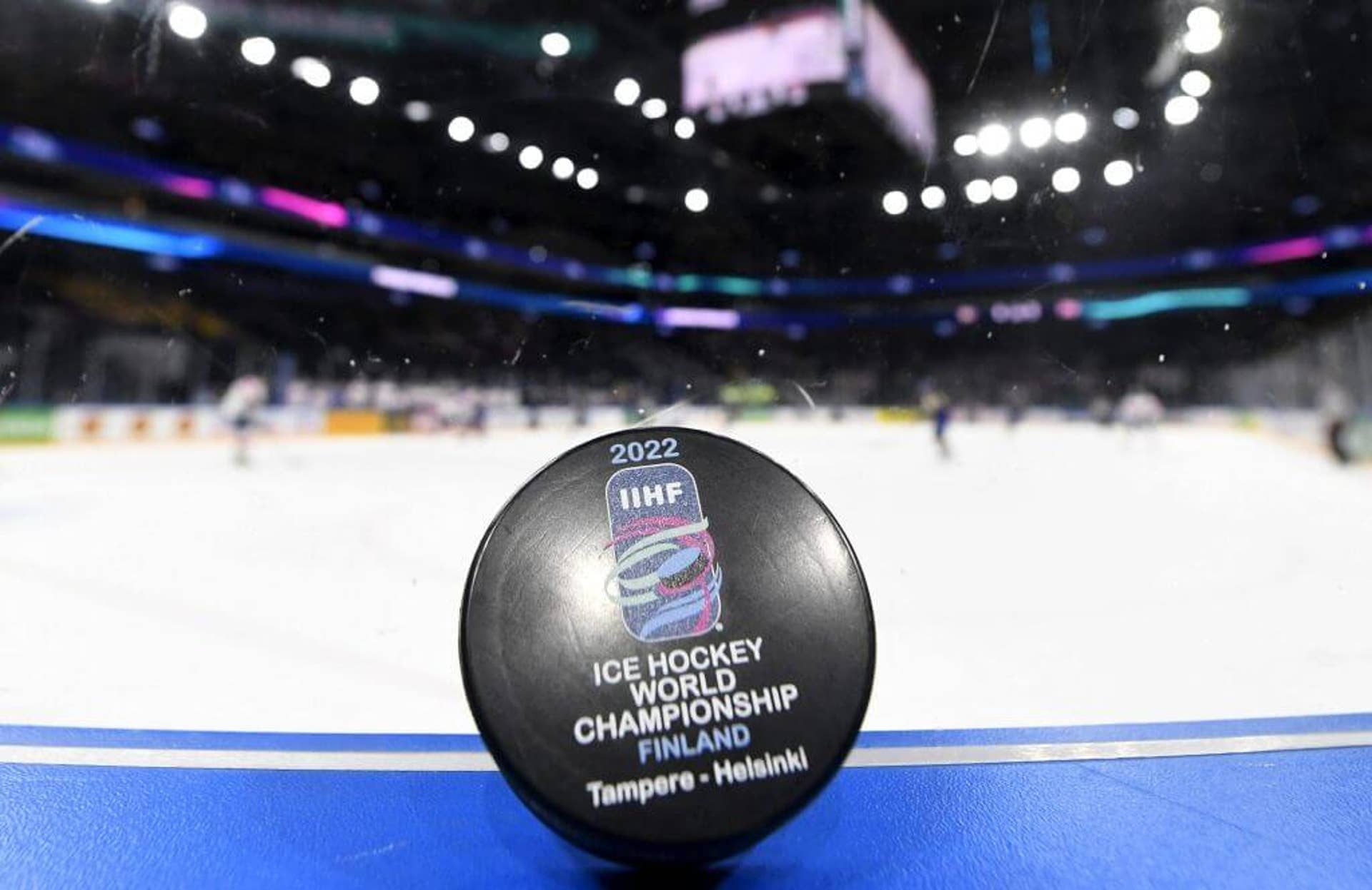 The official puck for the IIHF Ice Hockey World Championships in Tampere, Finland is seen leaning on the glass with the rink in the background.