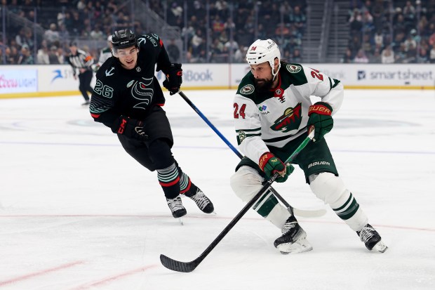 SEATTLE, WASHINGTON - DECEMBER 08: Ryan Winterton #26 of the Seattle Kraken defends Zach Bogosian #24 of the Minnesota Wild during the first period at Climate Pledge Arena on December 08, 2025 in Seattle, Washington. (Photo by Steph Chambers/Getty Images)