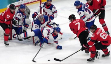 Feb 22, 2026; Milan, Italy; Dylan Larkin (21) and Connor Hellebuyck (37) of the United States battle for the puck against Devon Toews (7) and Brad Marchand (63) of Canada during the men's ice hockey gold medal game during the Milano Cortina 2026 Olympic Winter Games at Milano Santagiulia Ice Hockey Arena. Mandatory Credit: James Lang-Imagn Images