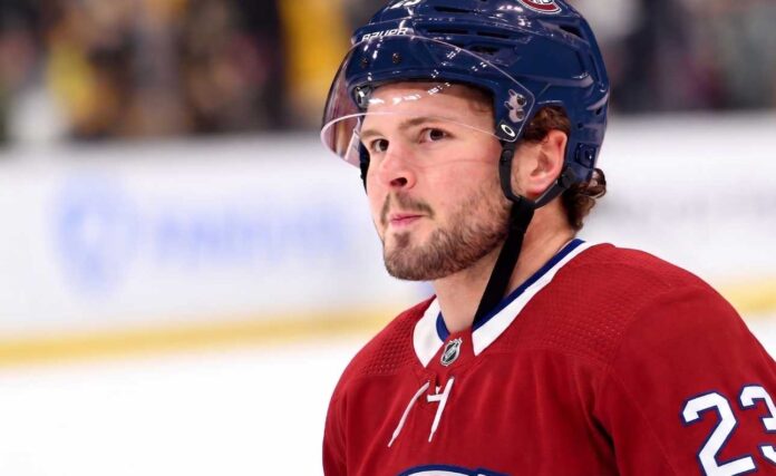 A detailed close-up view of NHL player Mason McTavish wearing a red Montreal Canadiens (Habs) home jersey with the number 23 on the shoulder and a blue Bauer helmet with the 'CH' logo, standing on an ice rink.