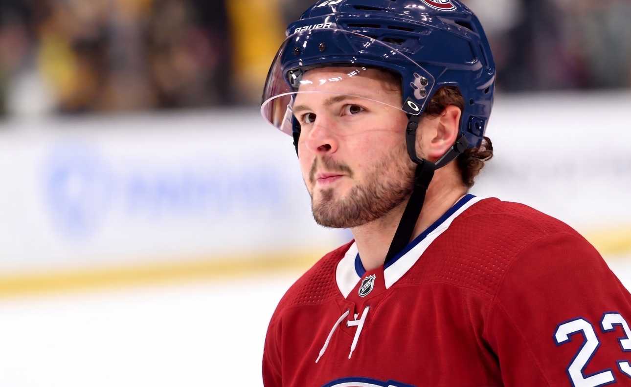 A detailed close-up view of NHL player Mason McTavish wearing a red Montreal Canadiens (Habs) home jersey with the number 23 on the shoulder and a blue Bauer helmet with the 'CH' logo, standing on an ice rink.