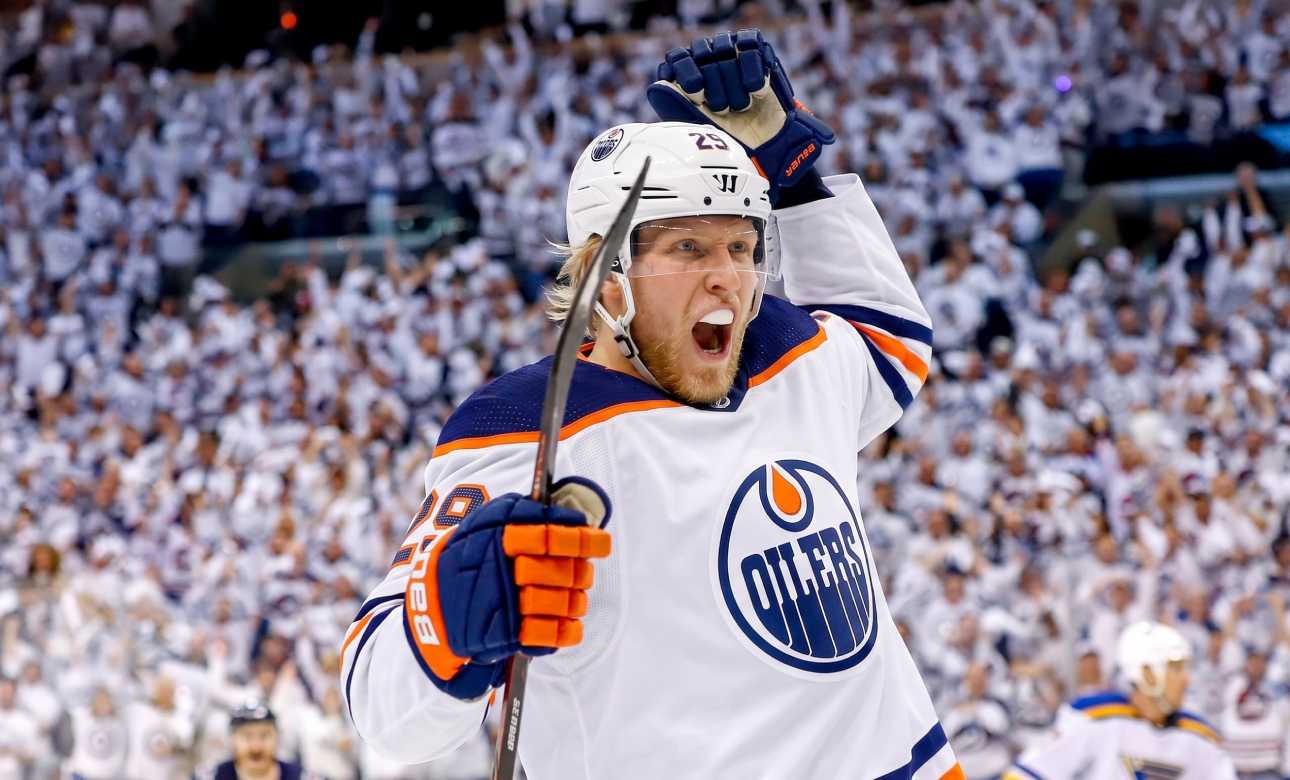 Conceptual action photo of NHL player Patrik Laine celebrating wildly in an Edmonton Oilers white away jersey and helmet, illustrating potential Free Agency landing spots for the pending UFA.