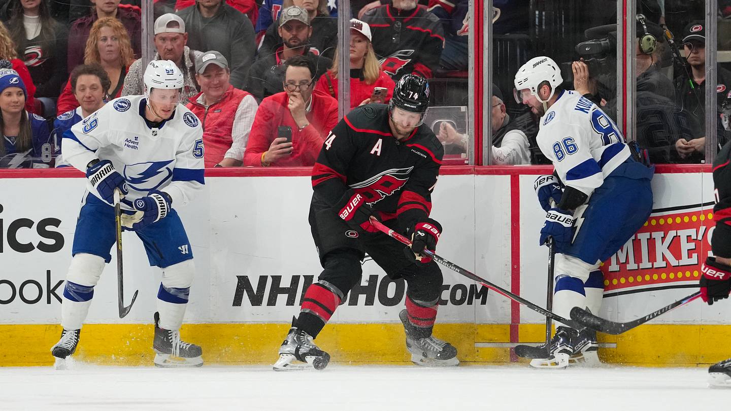 Feb 26, 2026; Raleigh, North Carolina, USA;  Carolina Hurricanes defenseman Jaccob Slavin (74) battles for the puck against Tampa Bay Lightning center Jake Guentzel (59) and right wing Nikita Kucherov (86) during the third period at Lenovo Center. Mandatory Credit: James Guillory-Imagn Images
