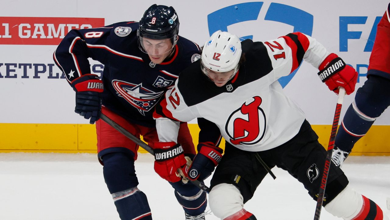 Columbus Blue Jackets' Zach Werenski, left, and New Jersey Devils' Cody Glass (12) fight for the puck during the third period of an NHL hockey game, Monday, Oct. 13, 2025, in Columbus, Ohio.