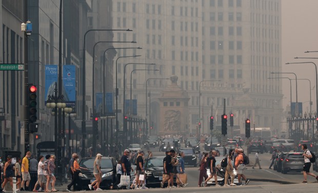 People cross North Michigan Avenue at East Randolph Street, July 16, 2026, in Chicago. The city was shrouded in wildfire smoke from Minnesota and Canada. (John J. Kim/Chicago Tribune)