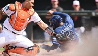Tampa Bay Rays' Junior Caminero (13) slides into home plate to score as Baltimore Orioles catcher Samuel Basallo, left, tags in the sixth inning of a baseball game Sunday, Aug. 23, 2026, in Baltimore. (AP Photo/Gail Burton)