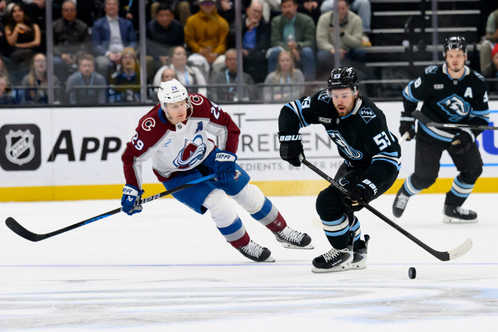Utah Mammoth left wing Michael Carcone (53) skates with the puck while being pursued by Colorado Avalanche center Nathan MacKinnon (29) during the second period of an NHL hockey game, Tuesday, Oct. 21, 2025, in Salt Lake City, Utah. (AP Photo/Tyler Tate)