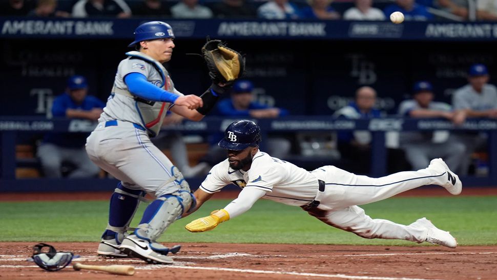 Tampa Bay Rays' Cedric Mullins, right, scores ahead of the throw to Toronto Blue Jays catcher Brandon Valenzuela on a bunt during the fourth inning of a baseball game Wednesday, Aug. 19, 2026, in St. Petersburg, Fla. (AP Photo/Chris O'Meara)