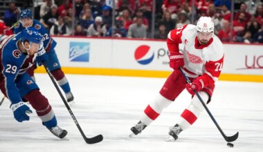 Detroit Red Wings center Dylan Larkin, right, looks to pass the puck as Colorado Avalanche center Nathan MacKinnon defends in the second period of an NHL hockey game, Monday, Jan. 16, 2023, in Denver. (AP Photo/David Zalubowski)