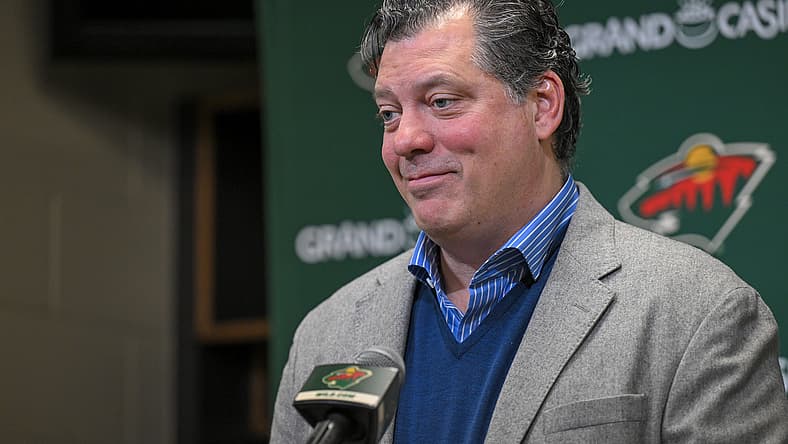 Minnesota Wild general manager Bill Guerin smiles while speaking to the media in front of a Wild logo backdrop