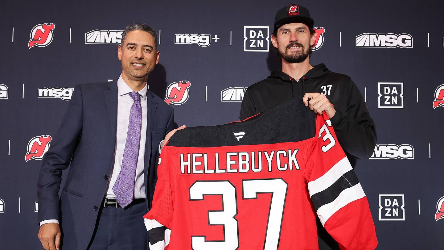 Connor Hellebuyck poses with New Jersey Devils GM Sunny Mehta