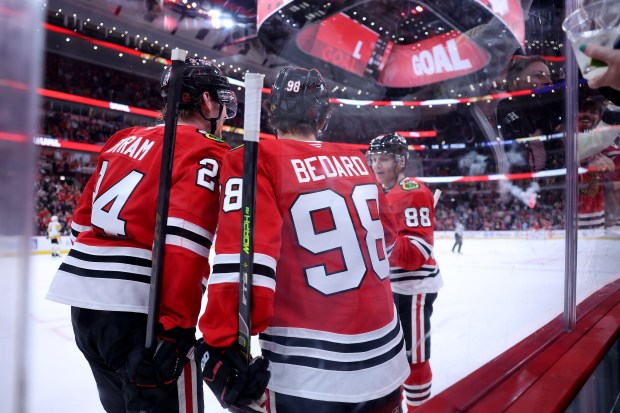 Chicago Blackhawks center Connor Bedard (98) celebrates with teammates Bowen Byram (24) and Patrick Kane (88) after Bedard's assist set up a goal by right wing Roman Kantserov in the first period of a game against the Pittsburgh Penguins at the United Center in Chicago on Oct. 13, 2026. (Chris Sweda/Chicago Tribune)
