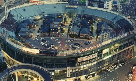 An old baseball stadium in Osaka, Japan transformed into a mini residential neighbourhood with fake streets, street lights and with cars parked outside homes.