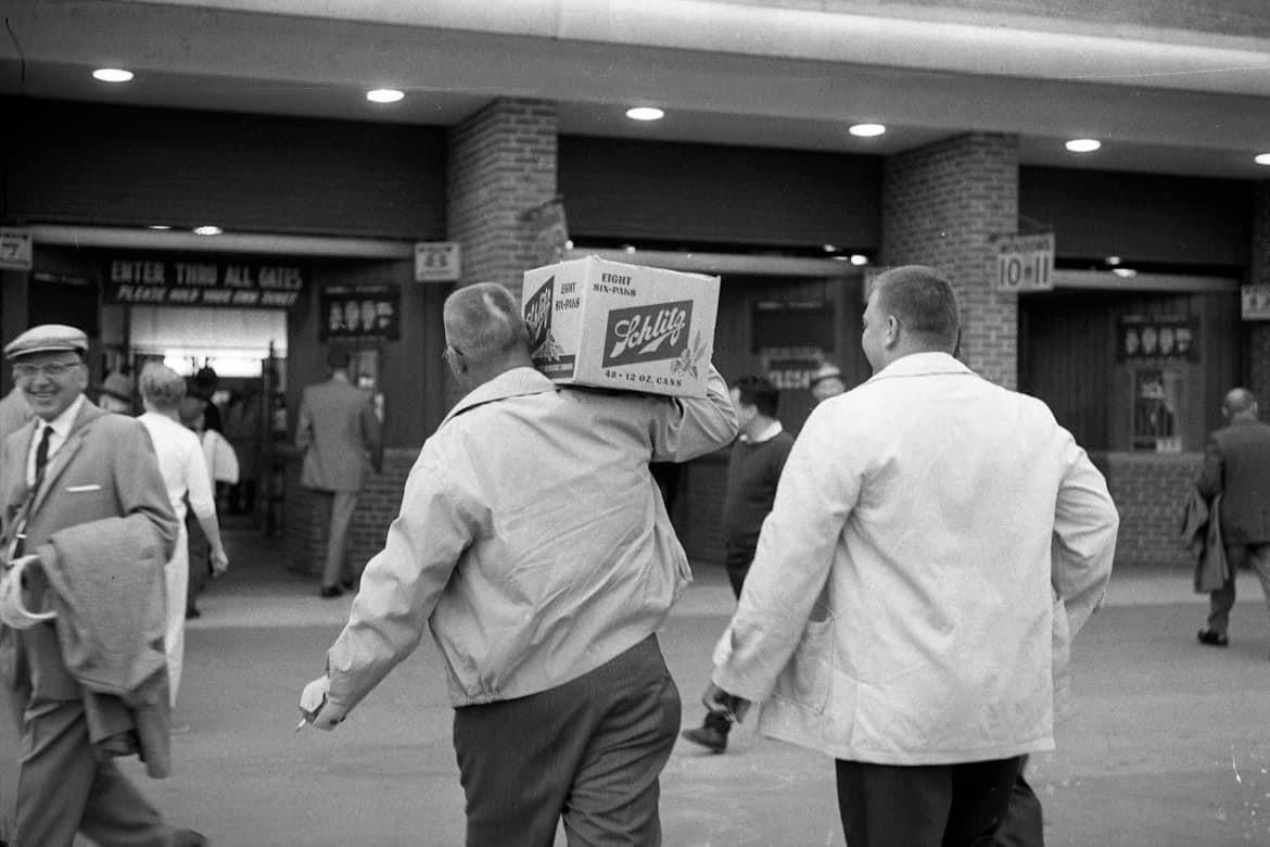 A fan carries a case of Schlitz into County Stadium before a game between the Milwaukee Braves and the Pittsburgh Pirates on June 8, 1962.