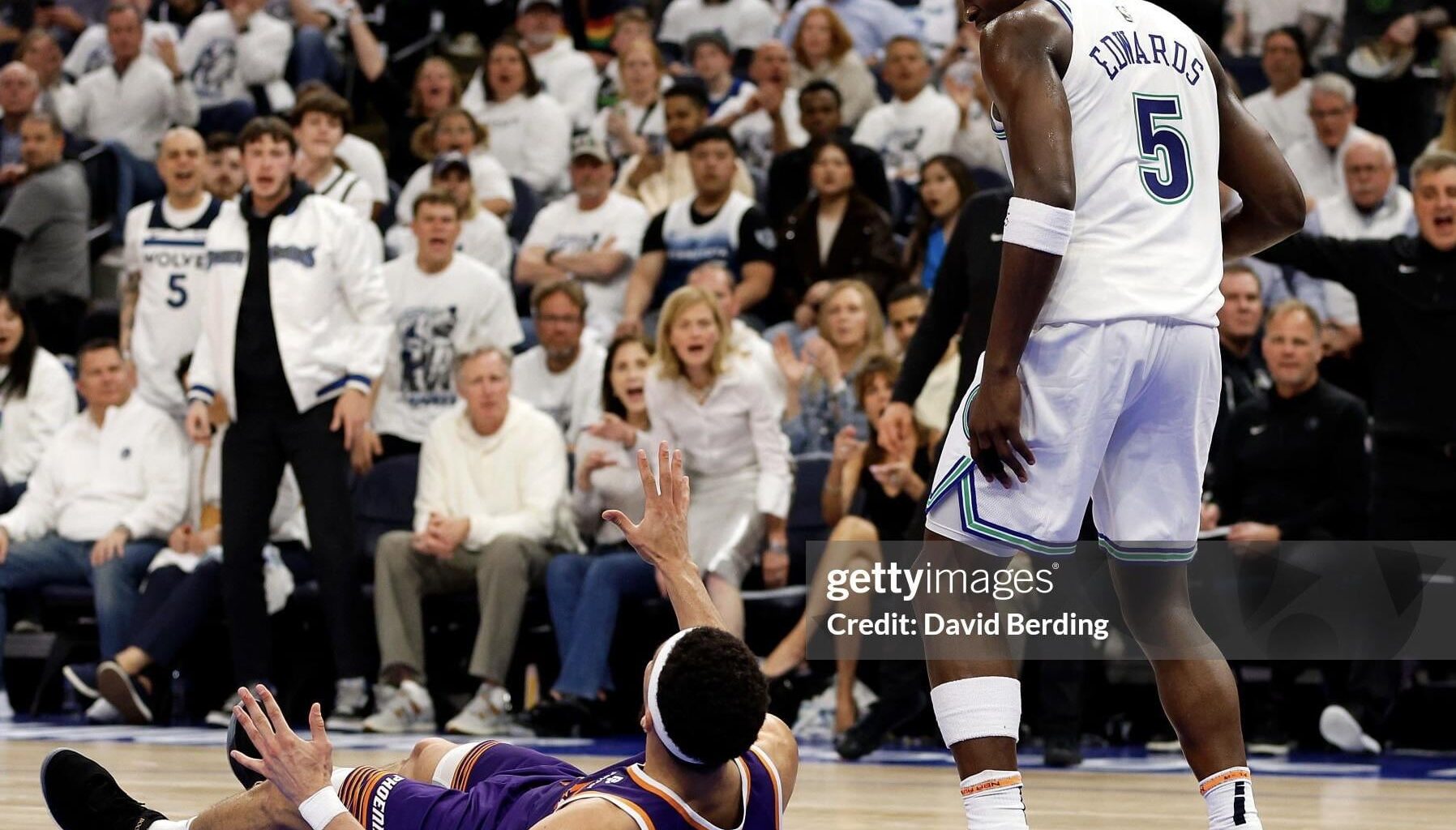 Anthony Edwards (villain) glares with disdain as Devin Booker (pathetic) begs for pity beneath him