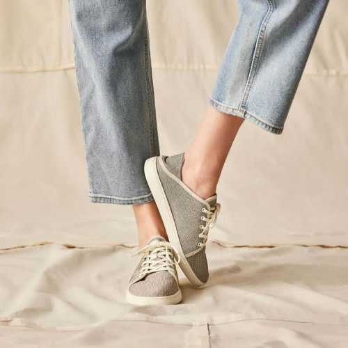 A person wearing casual gray sneakers and light blue jeans, standing on a neutral background.