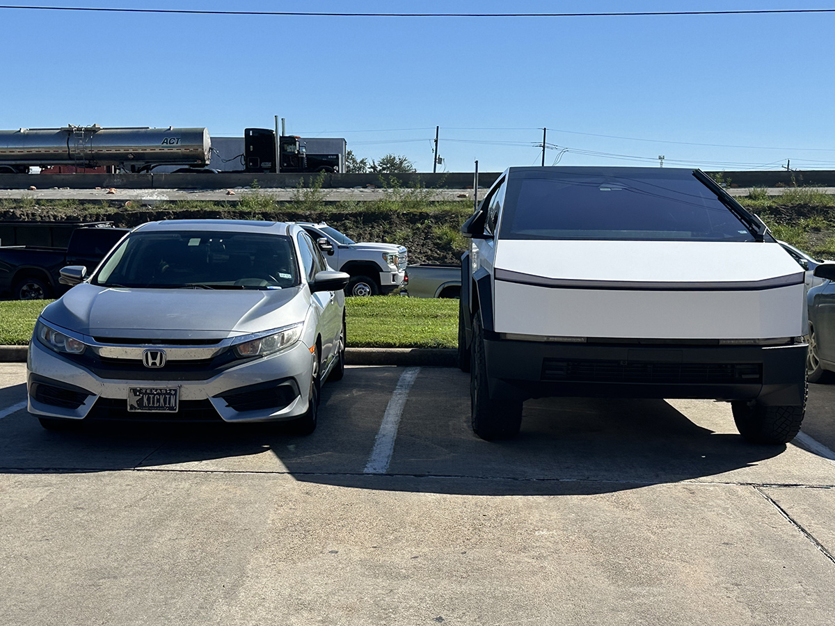 The ev tesla cybertruck looks massive next to a honda civic internal combustion engine passenger car. Photo by jerry jordan/kickin' the tires