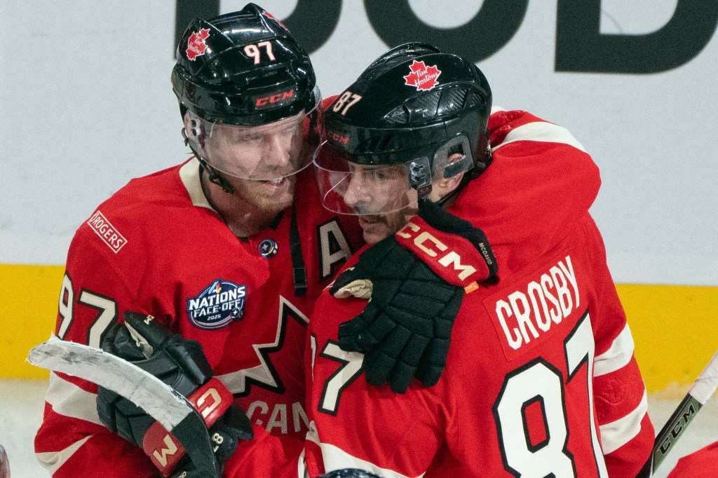 Canada's Connor McDavid (97) and Sidney Crosby (87) hug following their overtime win over Sweden during 4 Nations Face-Off hockey game in Montreal, Wednesday, Feb. 12, 2025.