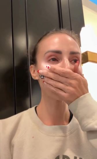 Woman crying, covering her mouth with her hand.