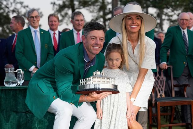 Rory McIlroy, of Northern Ireland, with his wife Erica Stoll, and daughter Poppy, holds the trophy after winning the Masters golf tournament, Sunday, April 13, 2025, in Augusta, Ga. (AP Photo/David J. Phillip)