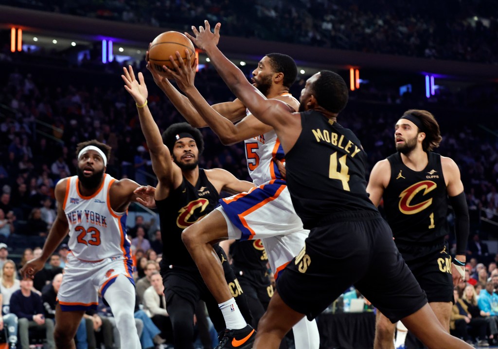 Mikal Bridges #25 of the New York Knicks goes up for a shot between Jarrett Allen #31 of the Cleveland Cavaliers and Evan Mobley #4 of the Cleveland Cavaliers during first half.