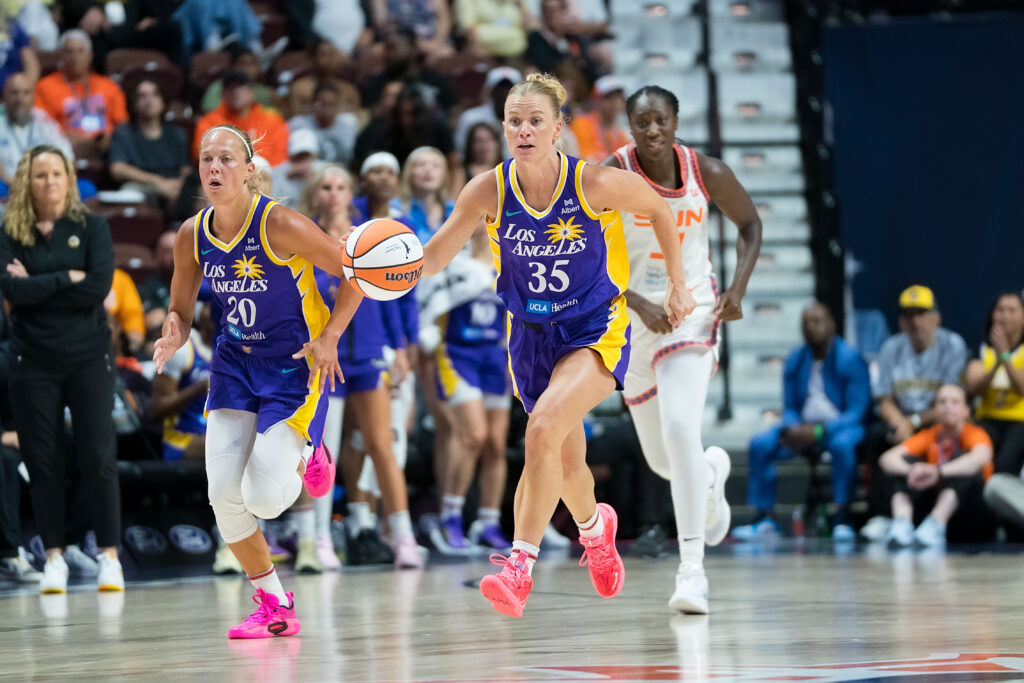Two players in Los Angeles Sparks gear dribble the ball down the court. 