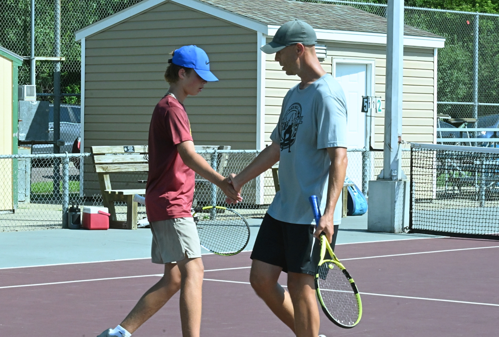 Gannon Pederson, left, and his father Todd low-five each other after winning a game during their doubles match at the Hub City Open Saturday, July 26 on the Northern State courts. Aberdeen Insider photo by Robb Garofalo.