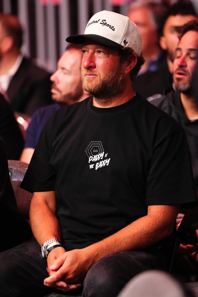 Man wearing a black t-shirt and a white baseball cap at a UFC event.