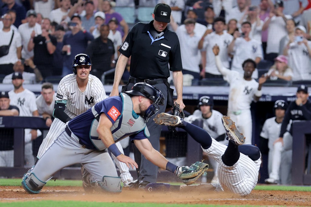 Seattle Mariners catcher tagging out a New York Yankees player at home plate.