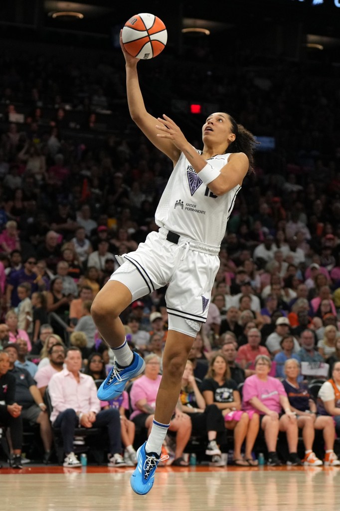 Golden State Valkyries forward Janelle Salaun shoots a layup. She is shwon from the side with a large but out of focus crowd behind her.