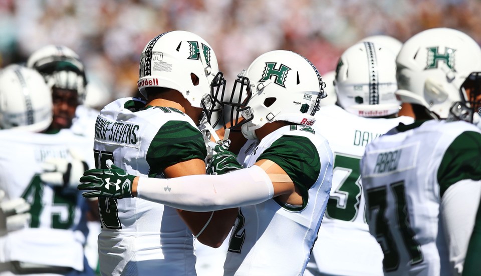 Hawaii Rainbow Warriors football players embracing.