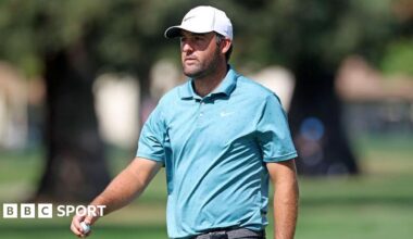 Scottie Scheffler wearing a white baseball cap and blue T-shirt