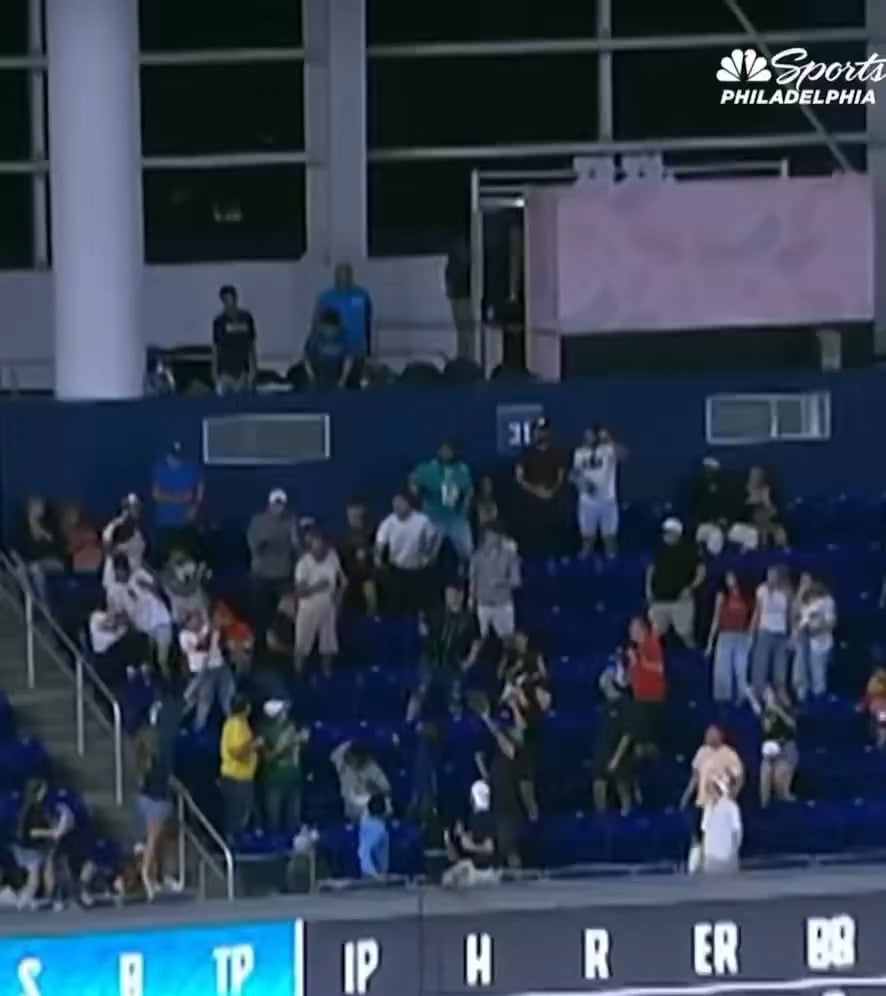 A Phillies fan retrieves a home run ball, while a woman nearby is upset that she didn't get it