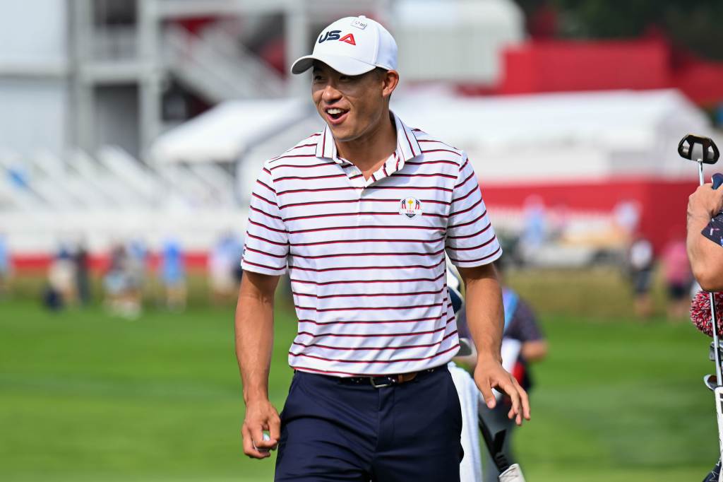 Collin Morikawa smiles on the golf course.