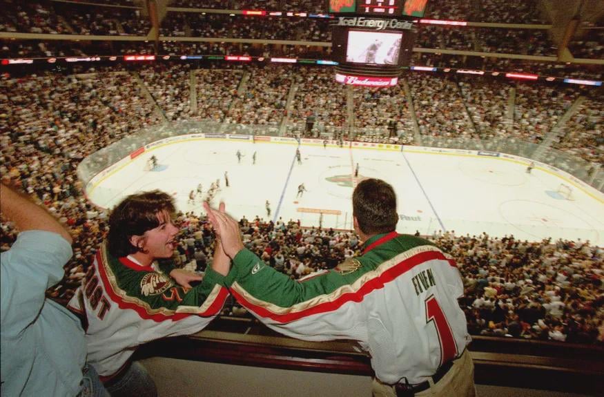 Minnesota Wild fans exchange high fives after the team scores its first ever goal - September 29, 2000