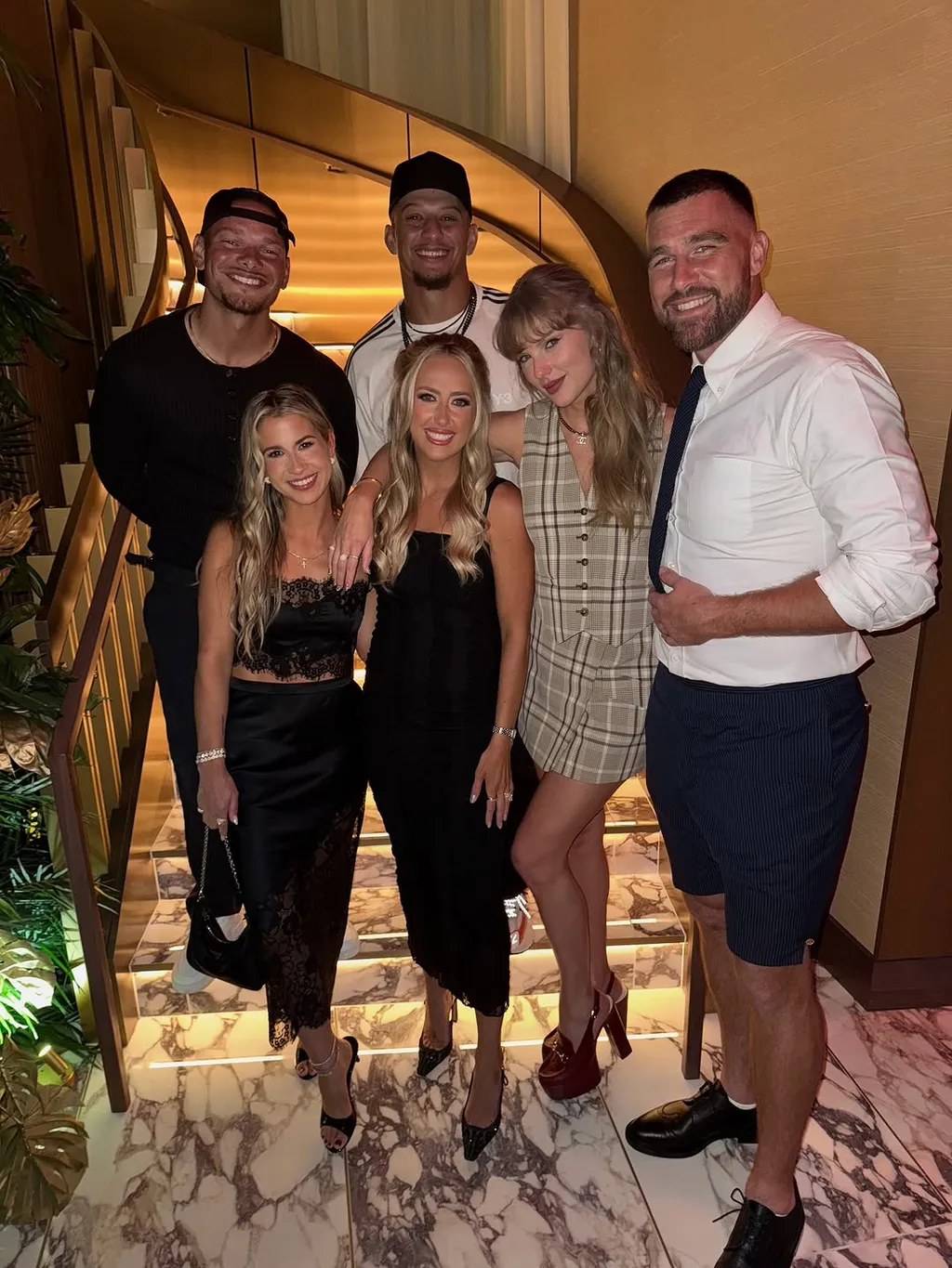 Taylor Swift posing with Travis Kelce and wearing a plaid two piece set with slingback heels