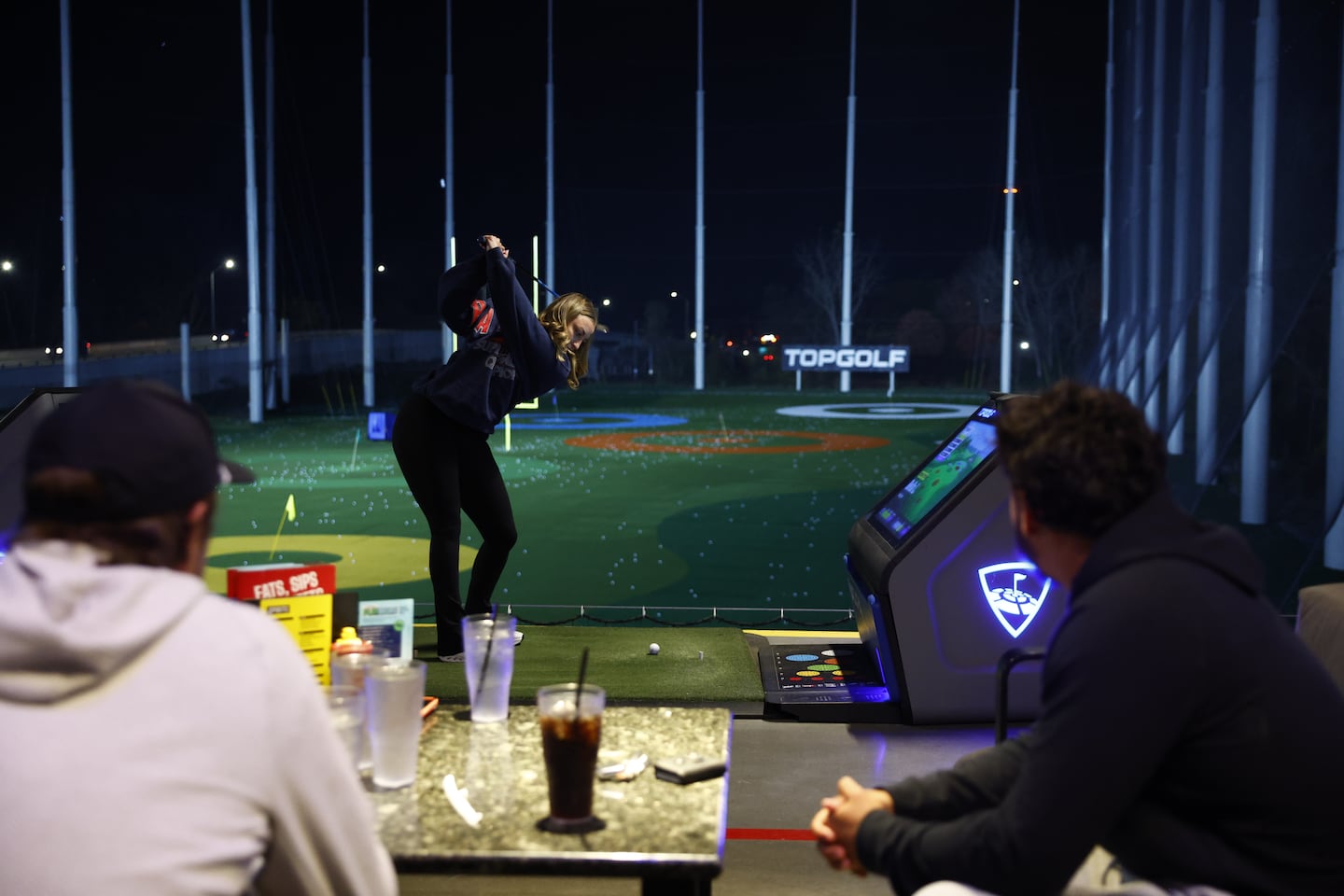 Bryce Baringer's wife, Bella, hits a shot during a recent outing at Topgolf.