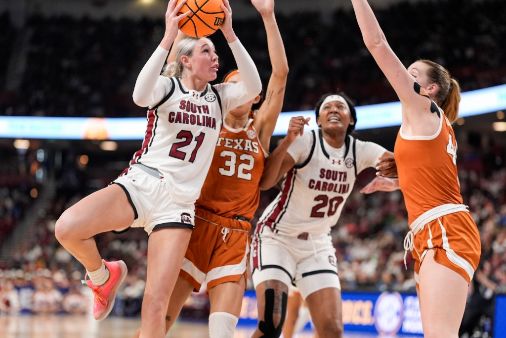 South Carolina forward Chloe Kitts holds the ball high with both hands as she looks to get a shot off between two Texas defenders.