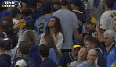 A lady standing still among the moving crowd looking incredibly proud as the Brewers take game 2 against the Cubs